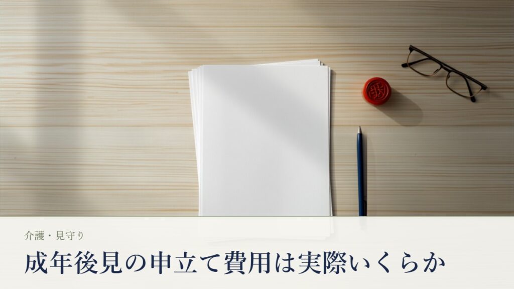 木目のテーブルに広げたA4の申立書類の束と朱肉・印鑑・老眼鏡・ボールペンの静物