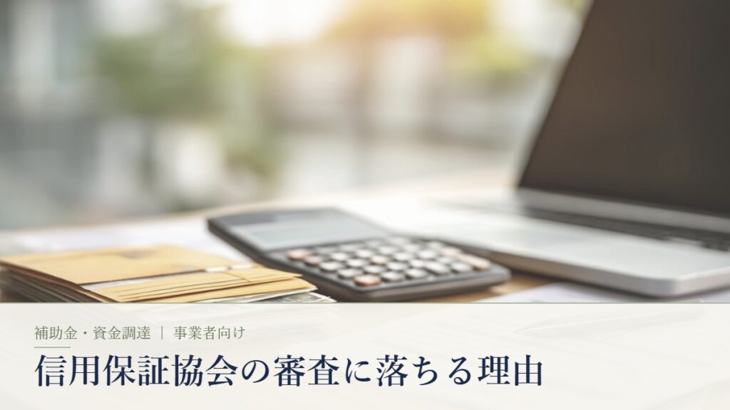 電卓とノートパソコンと書類が並ぶ日本のオフィスの机。信用保証協会の審査に落ちる理由の記事アイキャッチ